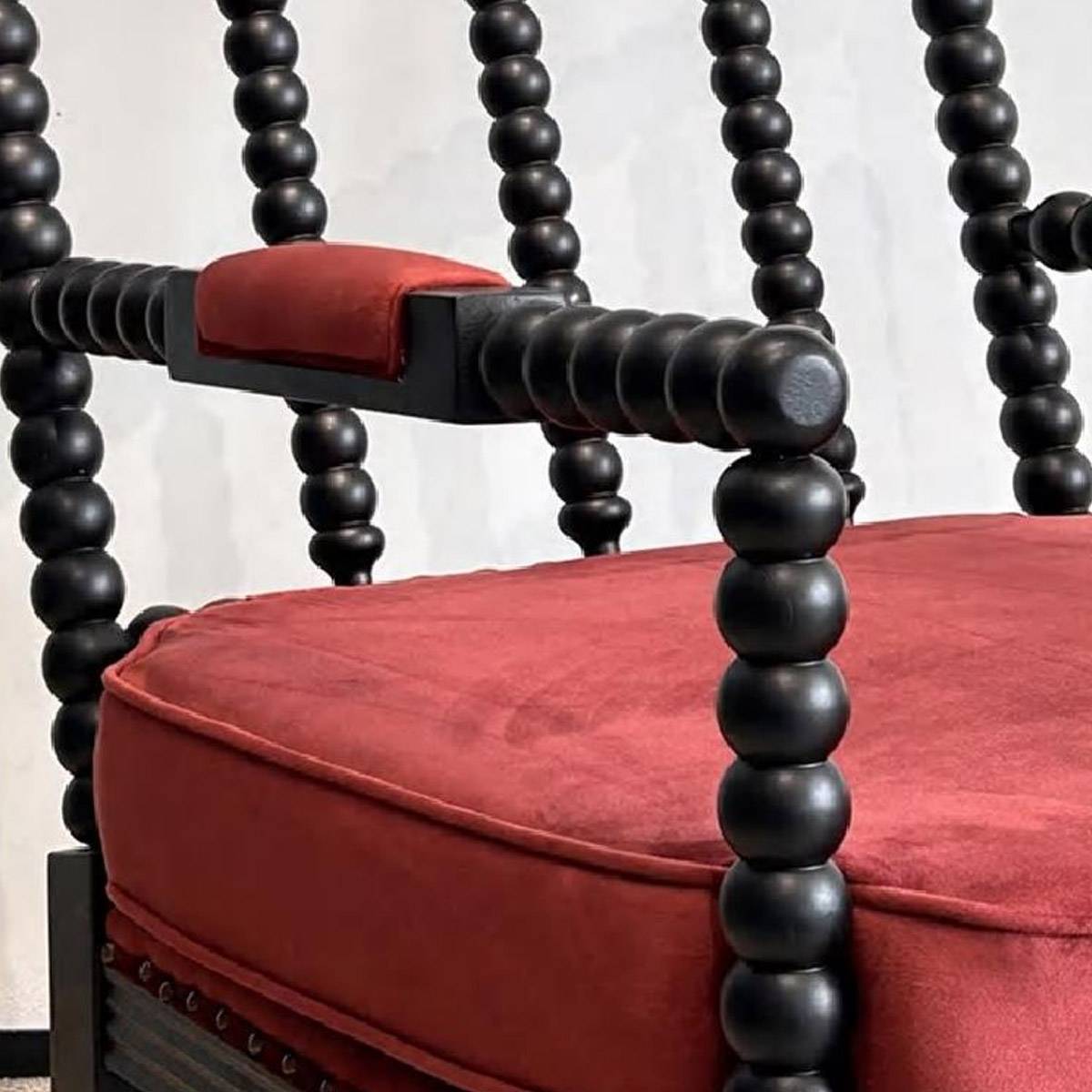 Close-up detail of the beaded armrest and red velvet seat cushion
