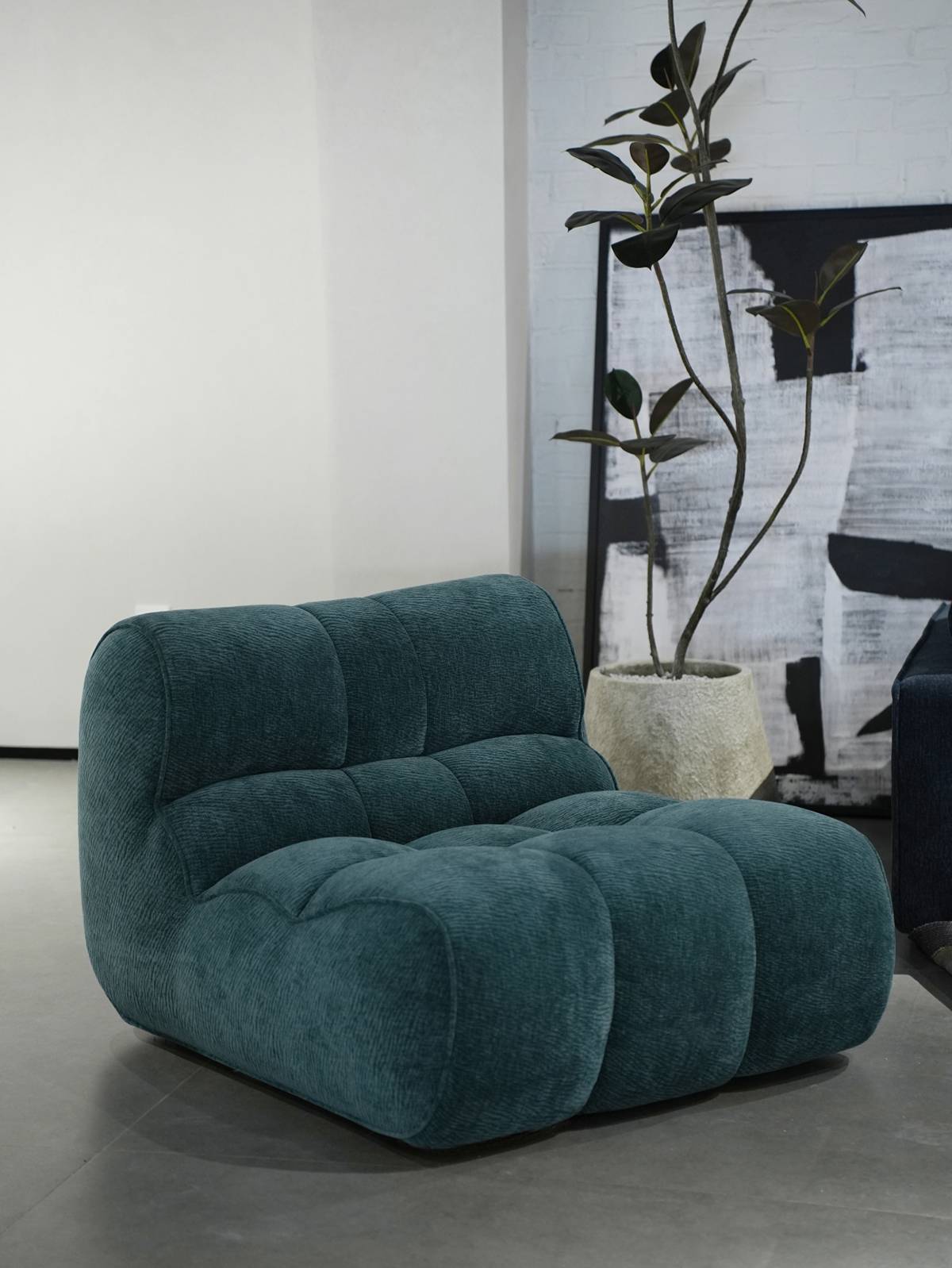 Teal lounge chair in a modern living room setting with a plant