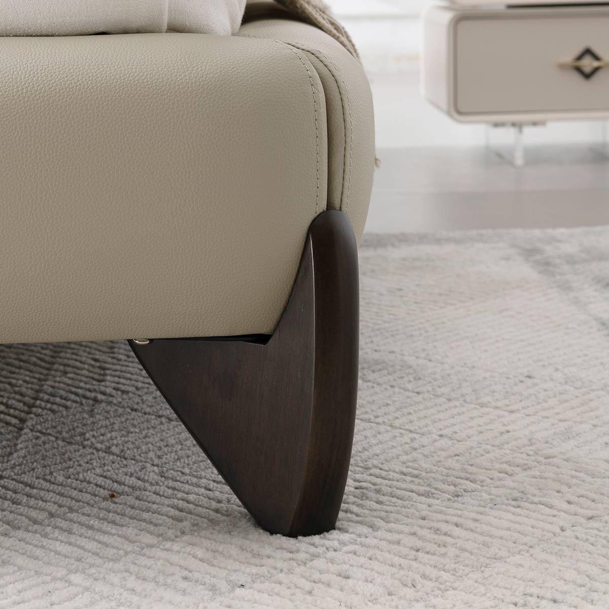Close-up detail of the dark wooden leg and leather upholstery stitching