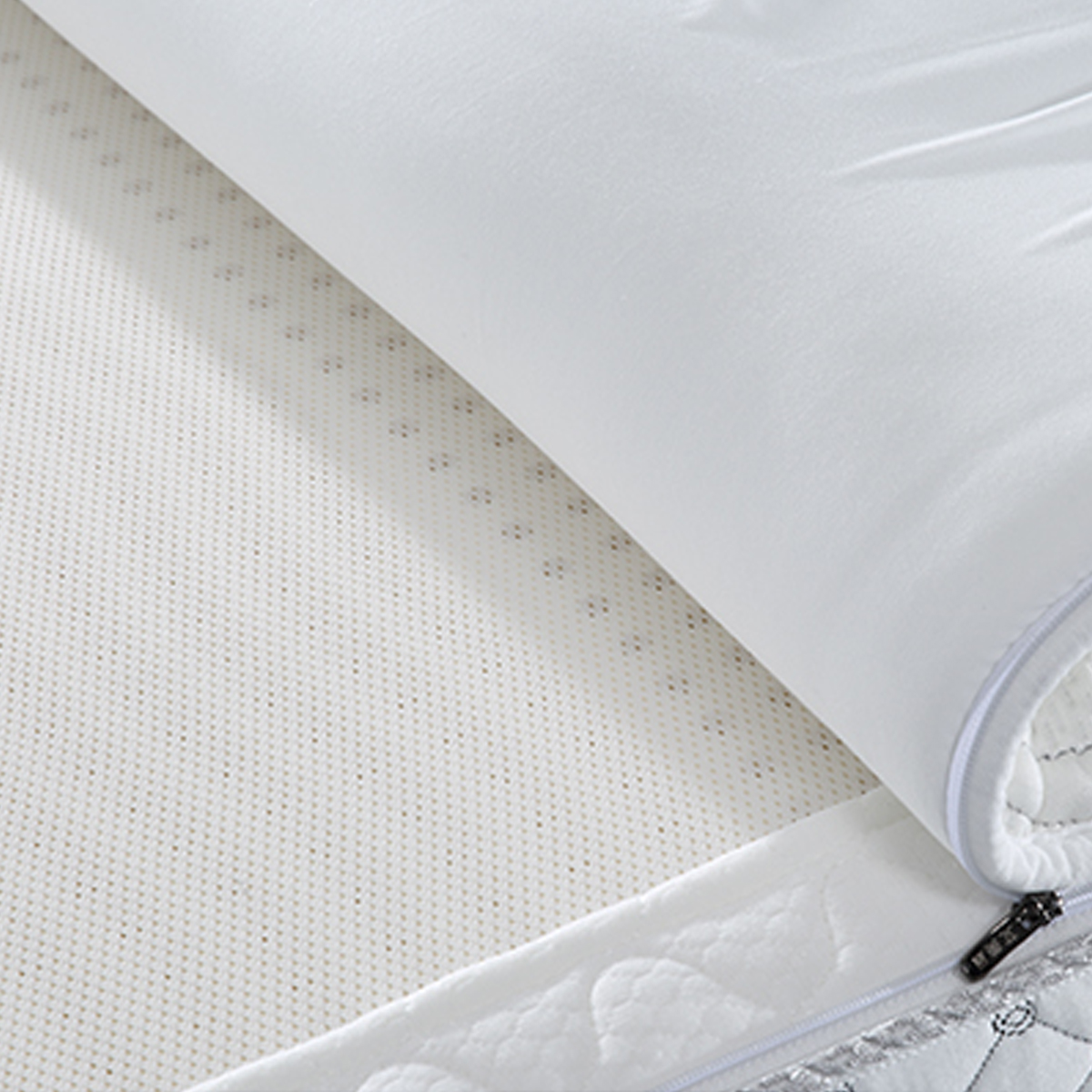 Close-up of the mattress corner showing the white fabric texture and zipper detail