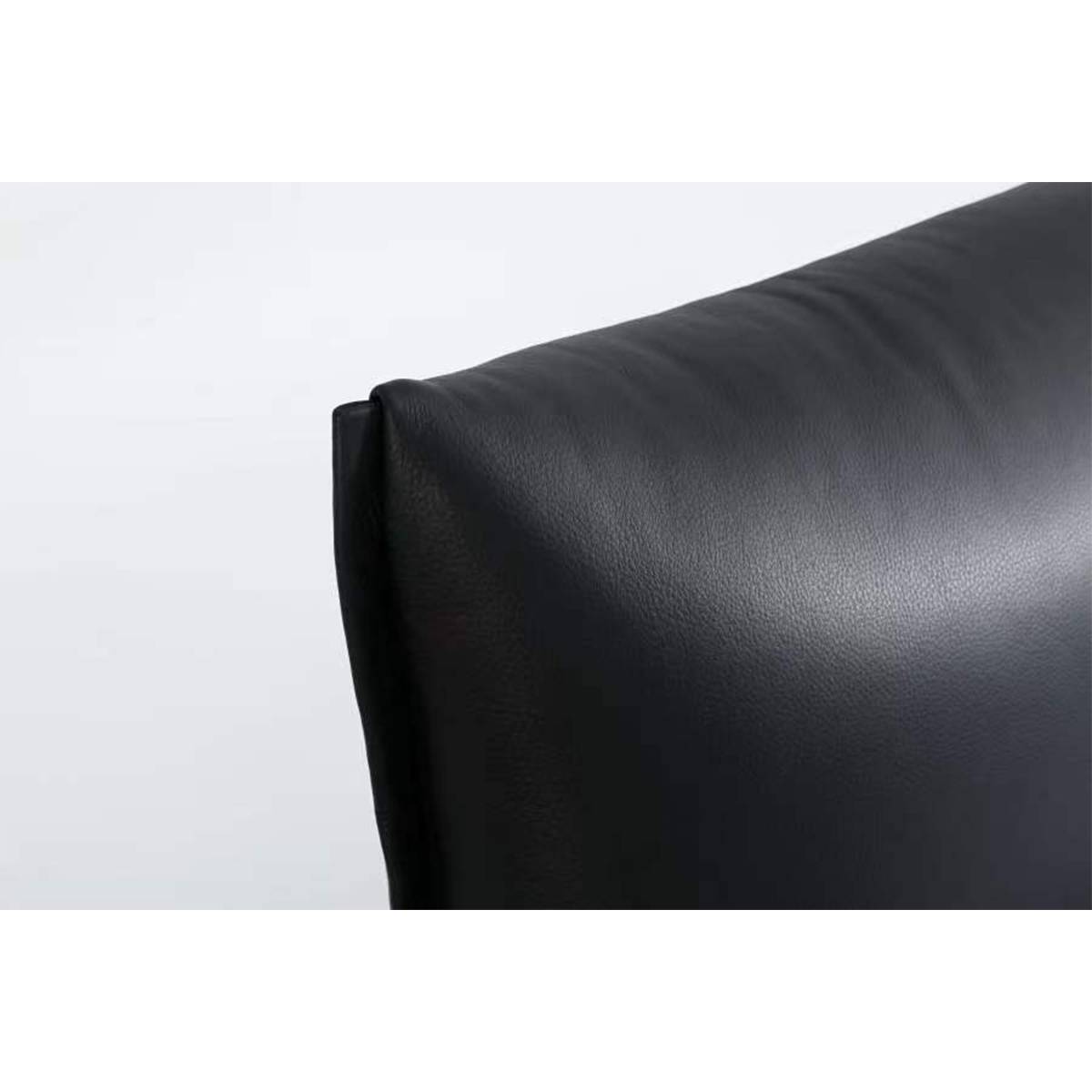 Close-up detail of the black leather headboard corner showing texture and stitching