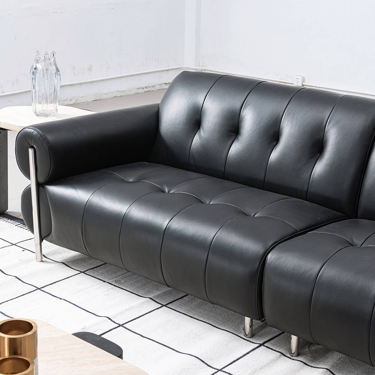 Side angle view of the black leather sofa showing the tufted back and seat