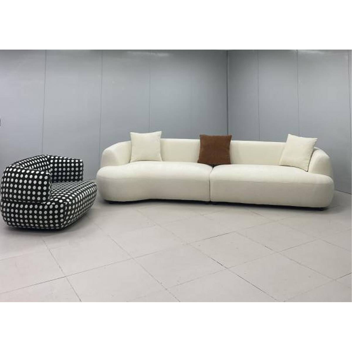 Black and white polka dot lounge chair placed next to a white sofa in a showroom