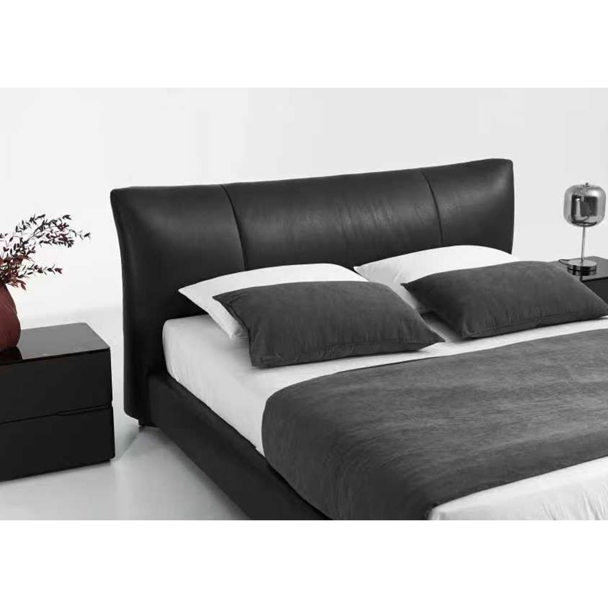 Front view of the black leather upholstered bed with white and grey bedding