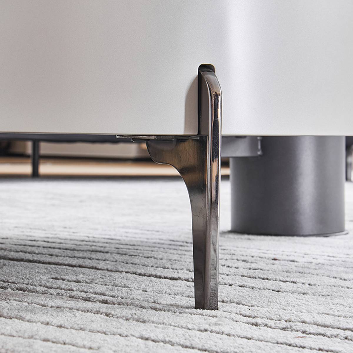 Close-up of the polished stainless steel leg and bracket detail of the coffee table.