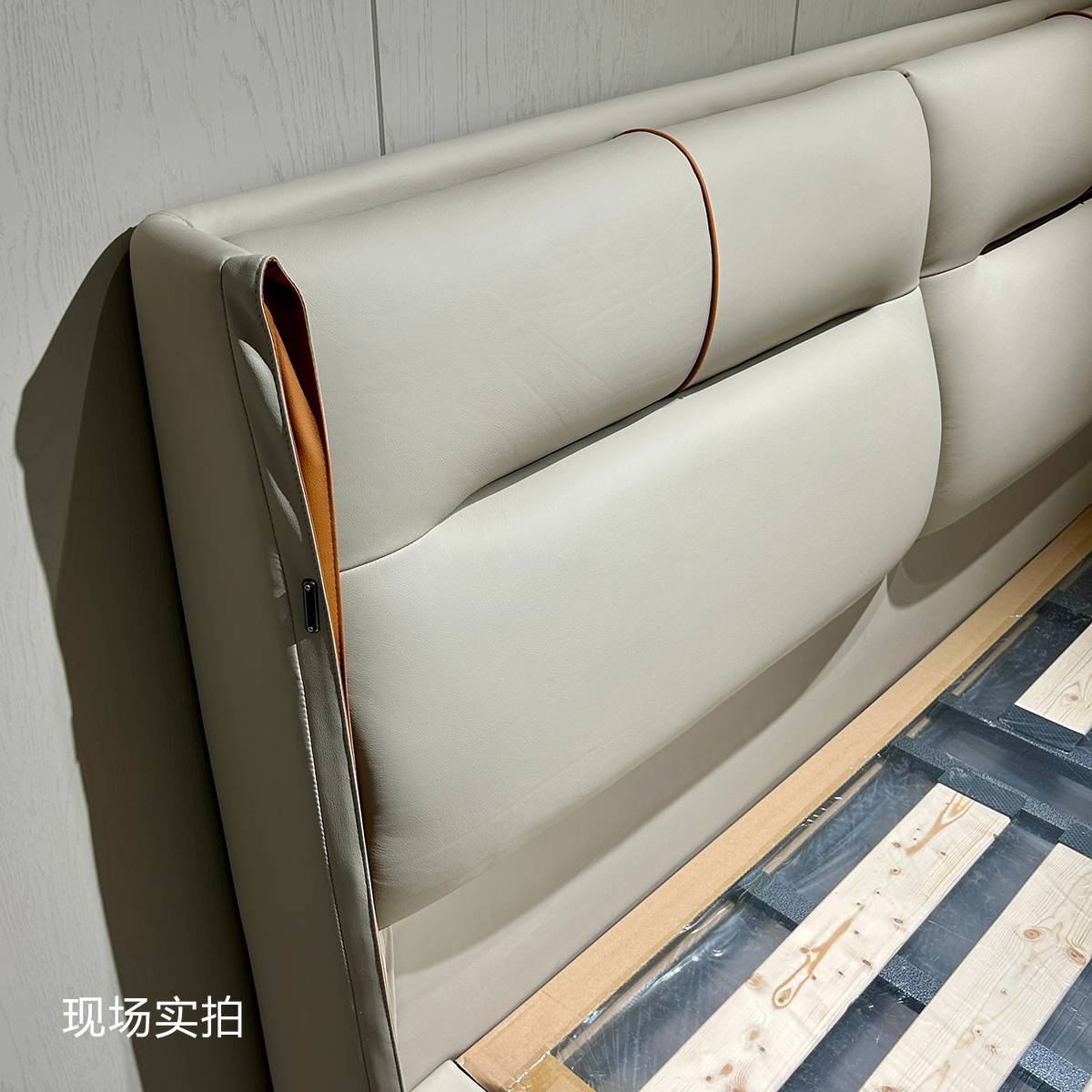 Close-up of the beige leather headboard showing the zipper detail and internal structure