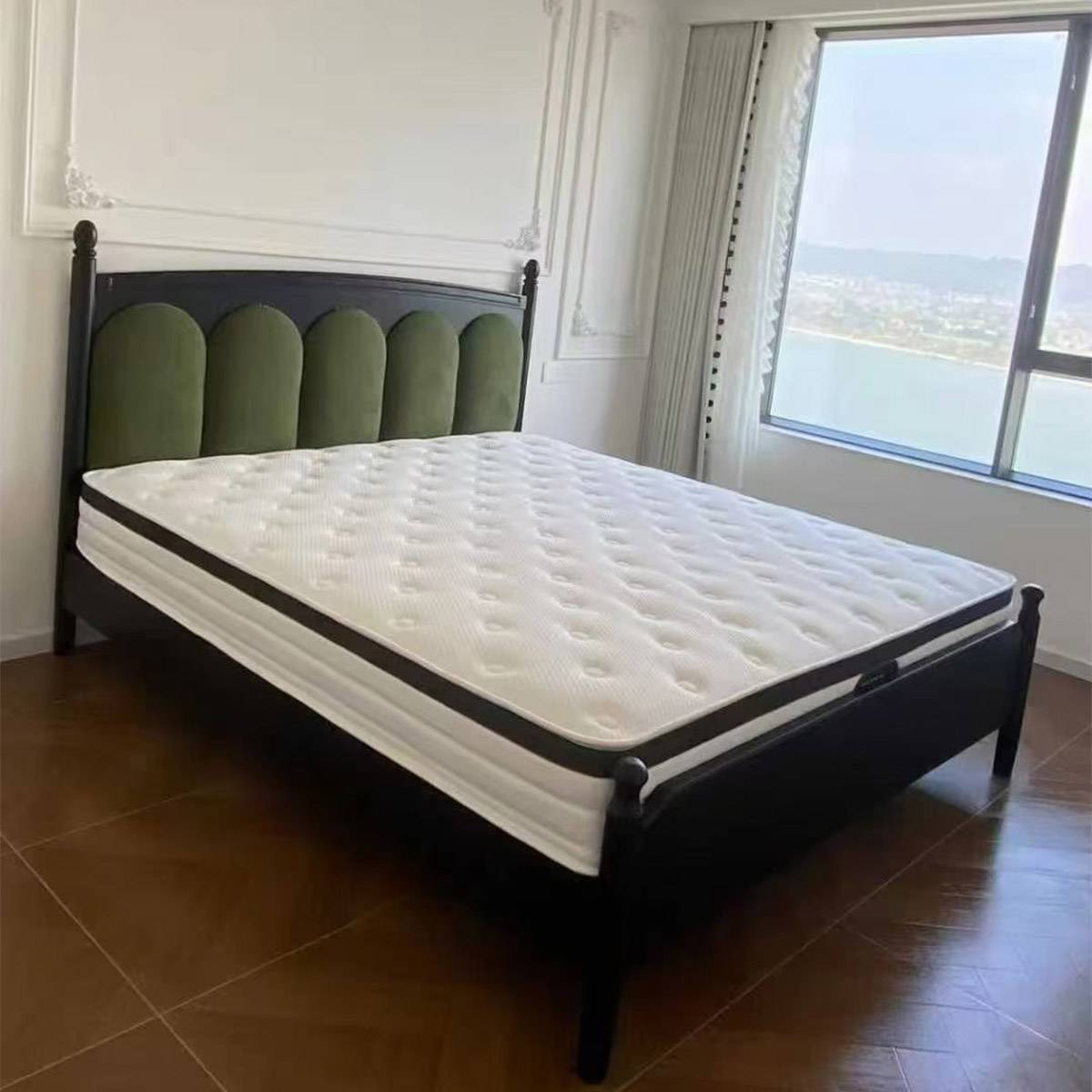Black wood mid-century bed frame with mattress and green velvet headboard