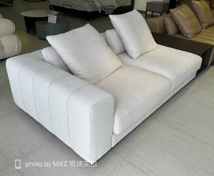 Close-up of the white fabric sofa showing the piano-key tufting and pillows