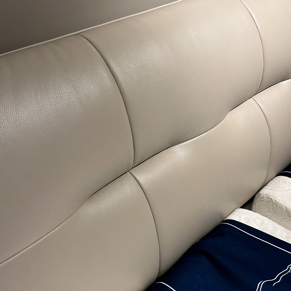 Close-up view of the beige top-grain leather headboard showing texture and stitching details