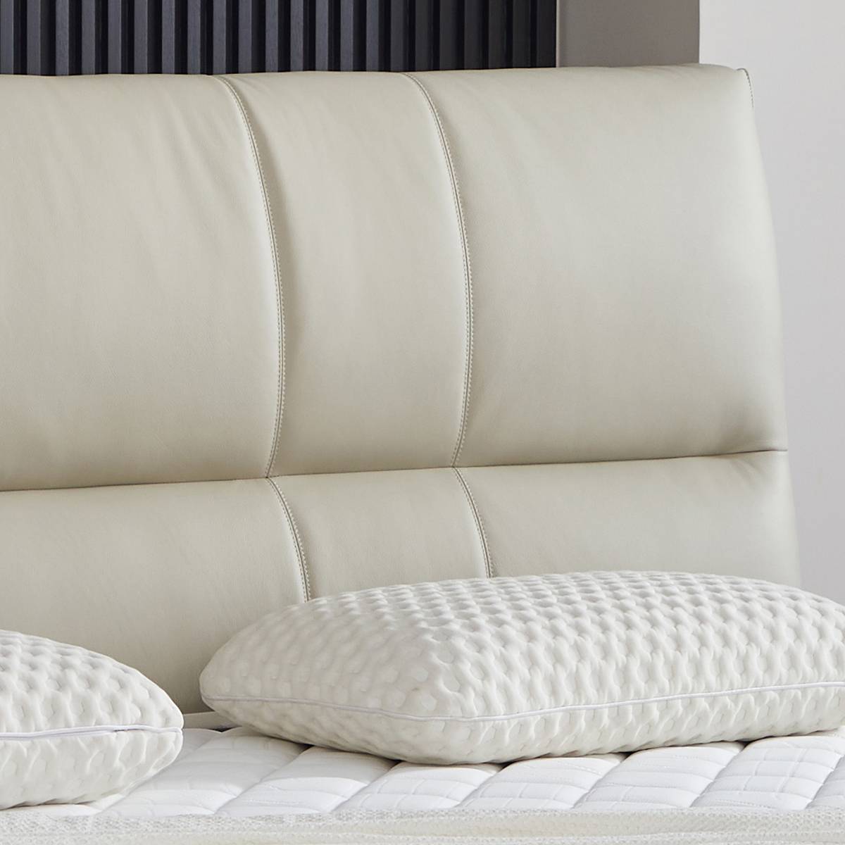 Close-up of the cream-colored leather headboard showing stitching details and texture