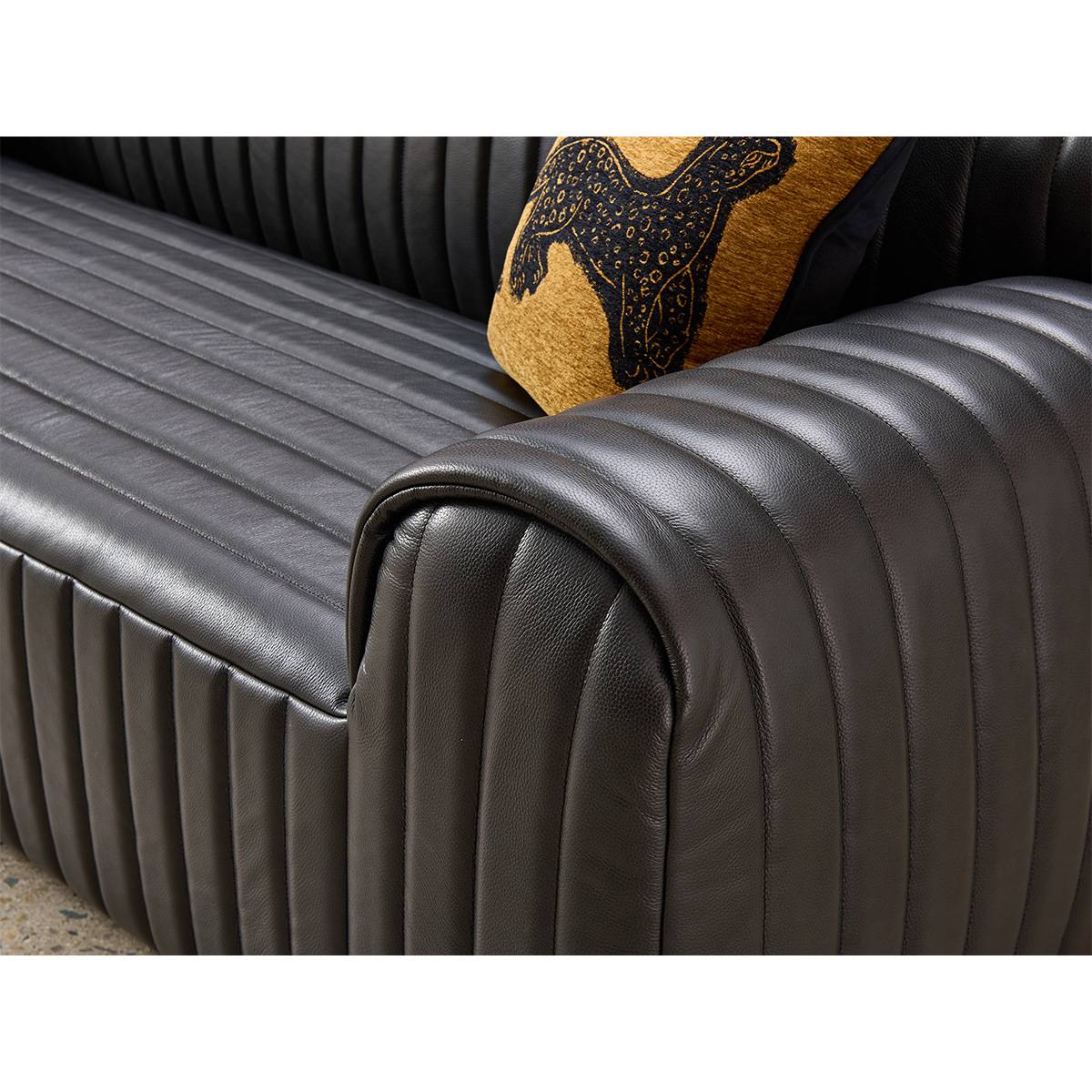 Close-up view of the black leather sofa armrest showing vertical channel tufting and texture