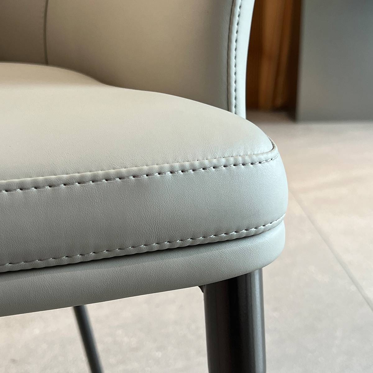 Close-up detail of the beige leather seat cushion and stitching.