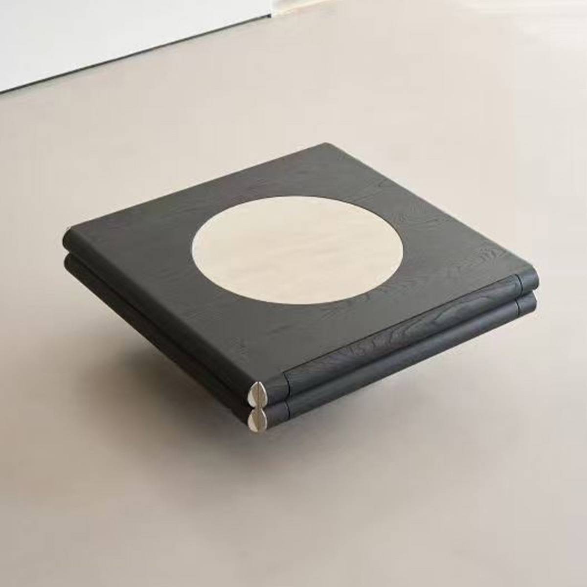Angled view of the coffee table on a light floor, highlighting the stainless steel accents on the corners