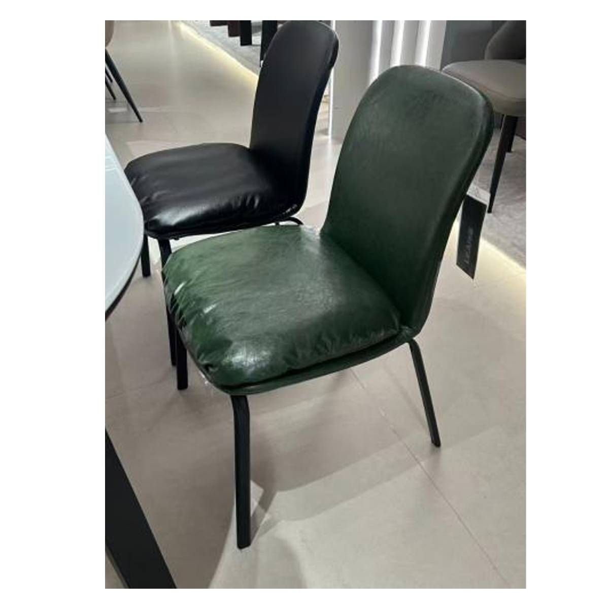 Comparison of dark green and black dining chairs in a showroom setting