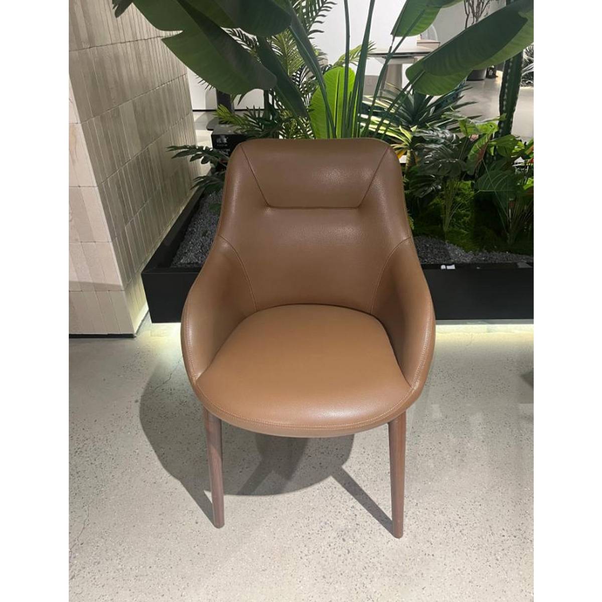 Brown modern dining chair with walnut legs in a modern interior setting
