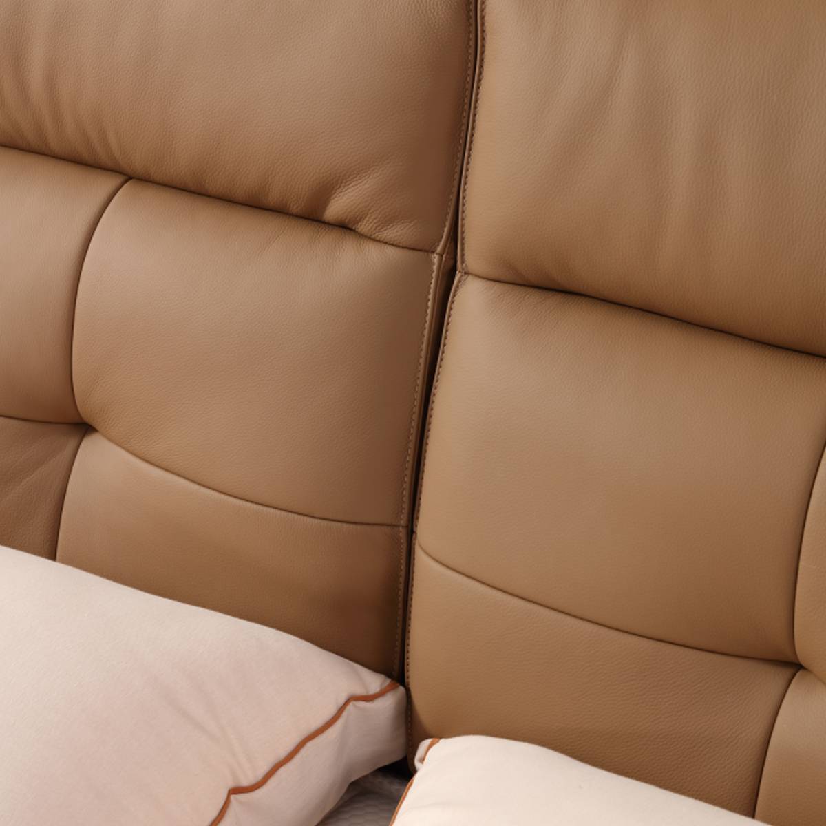 Close-up of the tan leather headboard showing tufted stitching and texture