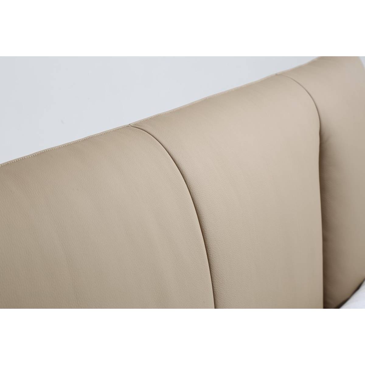 Close-up detail of the beige leather upholstery and stitching on the bed headboard