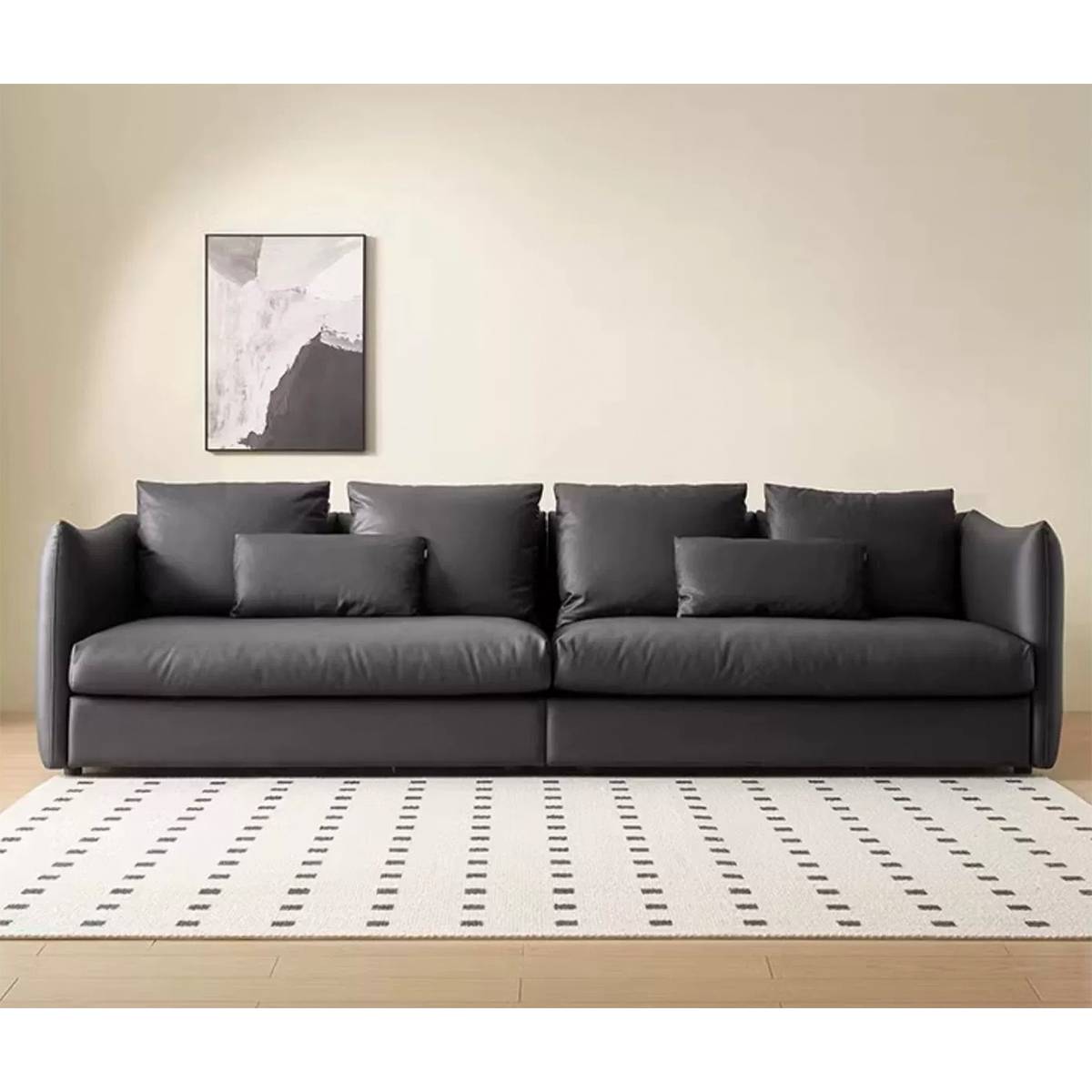 Front view of a black straight leather sofa with multiple cushions in a minimalist living room setting.