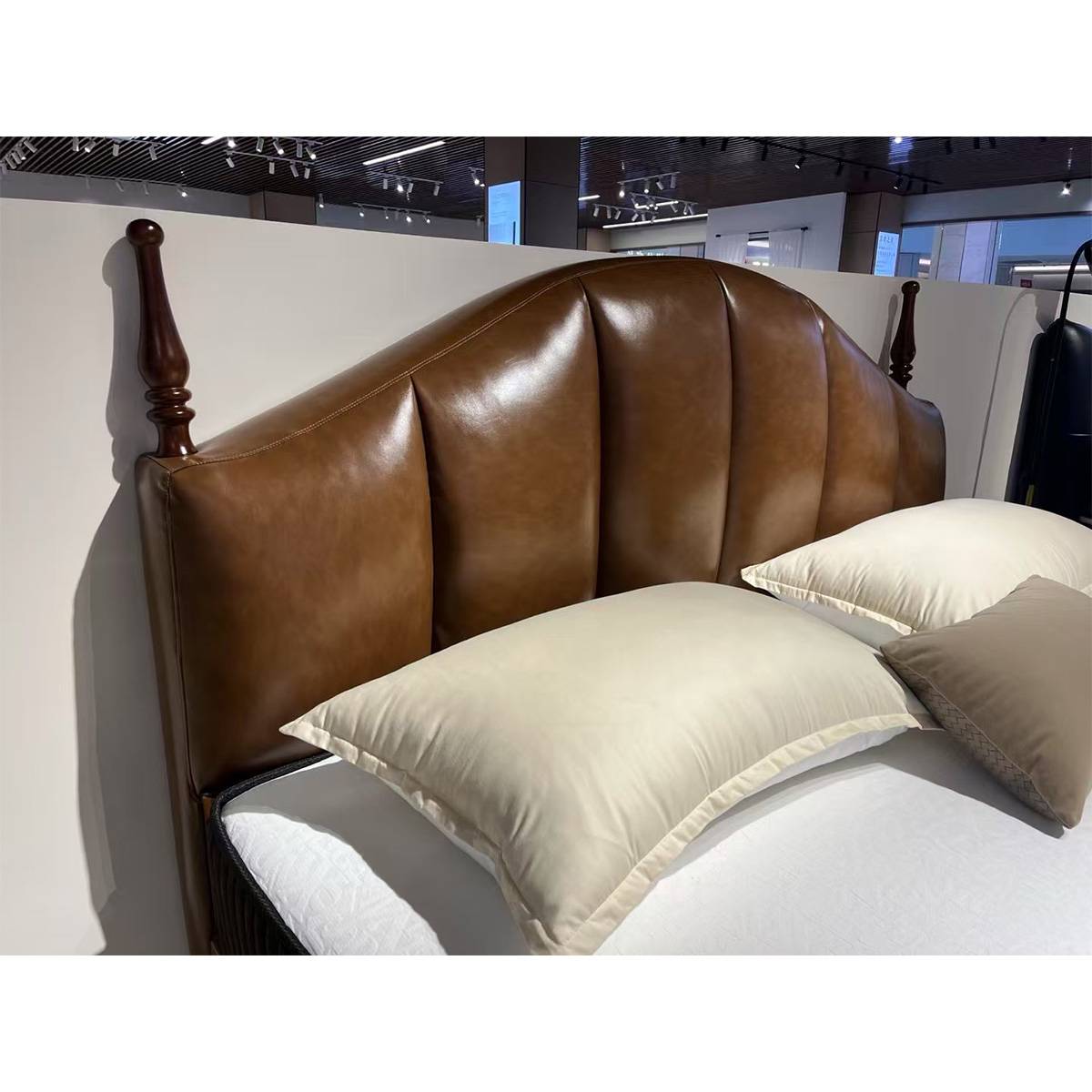 Close-up of the curved leather headboard and wooden posts