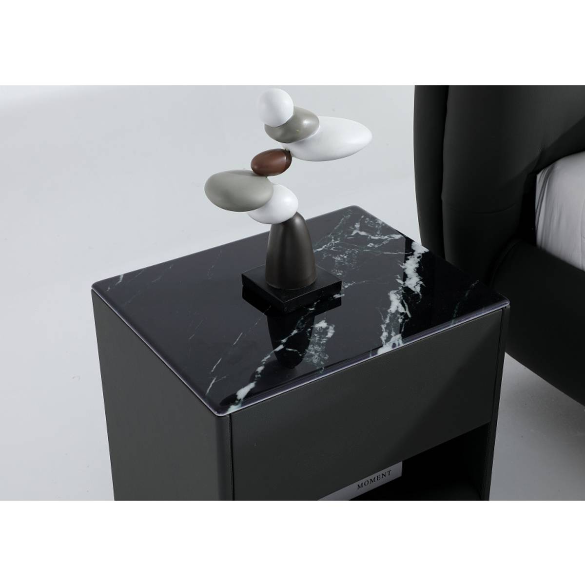 Close-up detail of the black marble-topped bedside table with a decorative stone sculpture
