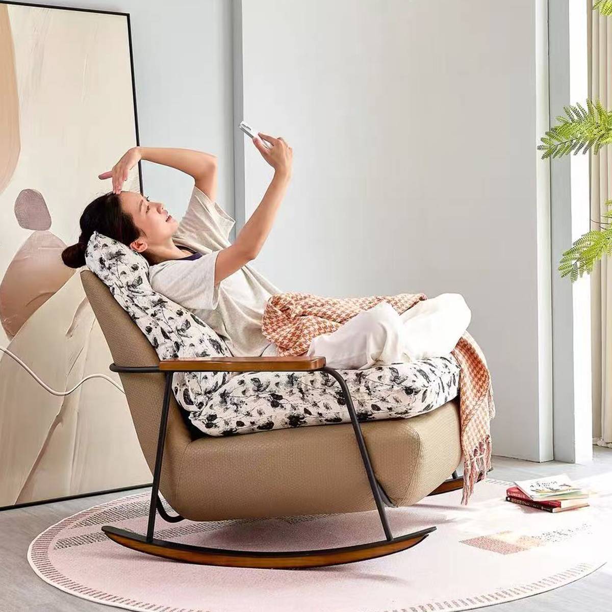 Model relaxing in the rocking lounge chair while looking at a phone