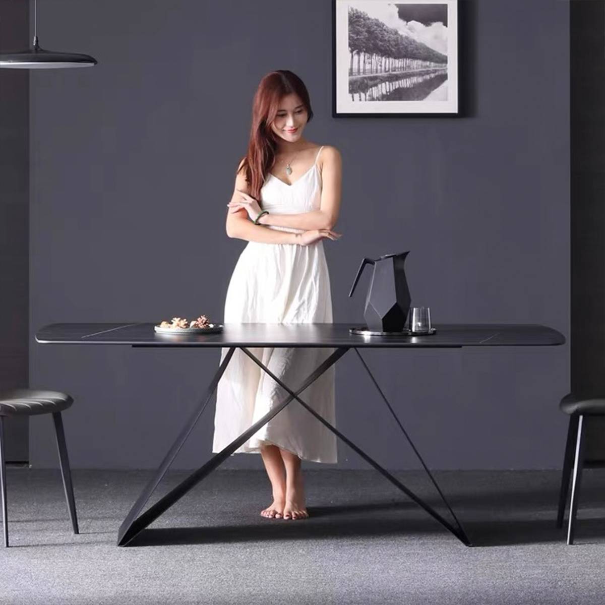 Model standing behind a dark grey dining table with a geometric black pitcher