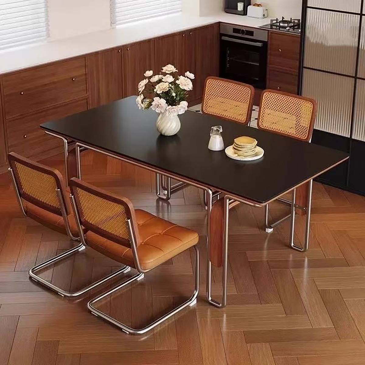 Black dining table with matching rattan-back chairs in a kitchen setting