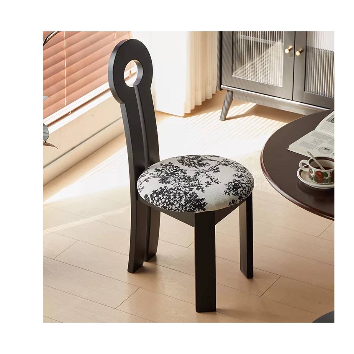 Close-up of the black keyhole chair with floral seat cushion next to a round table