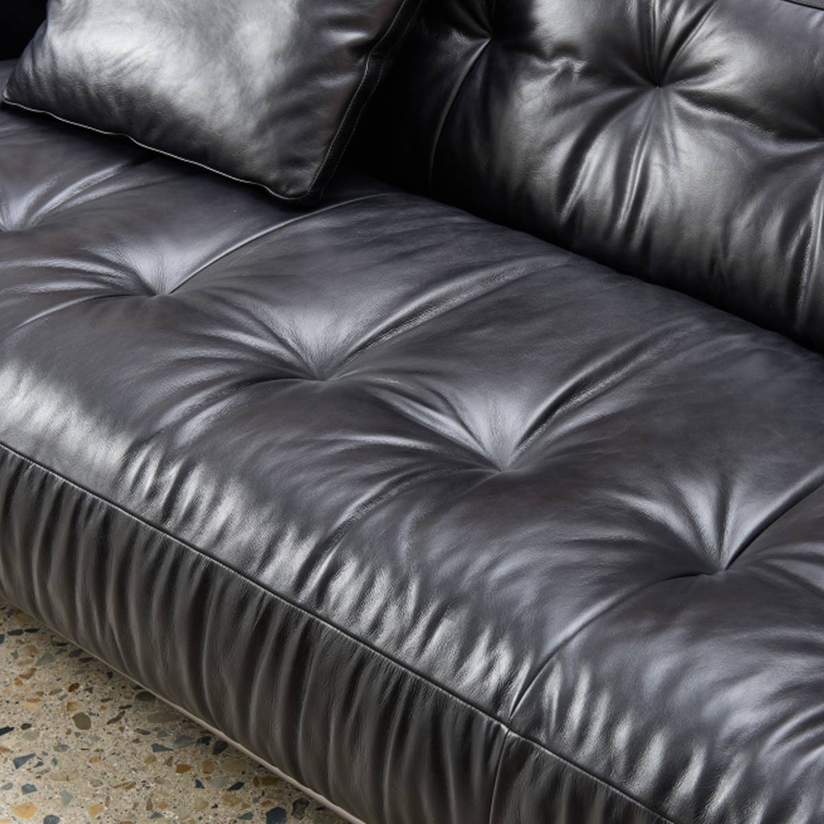 Close-up view of the black oil wax leather sofa showing the tufted texture and leather grain