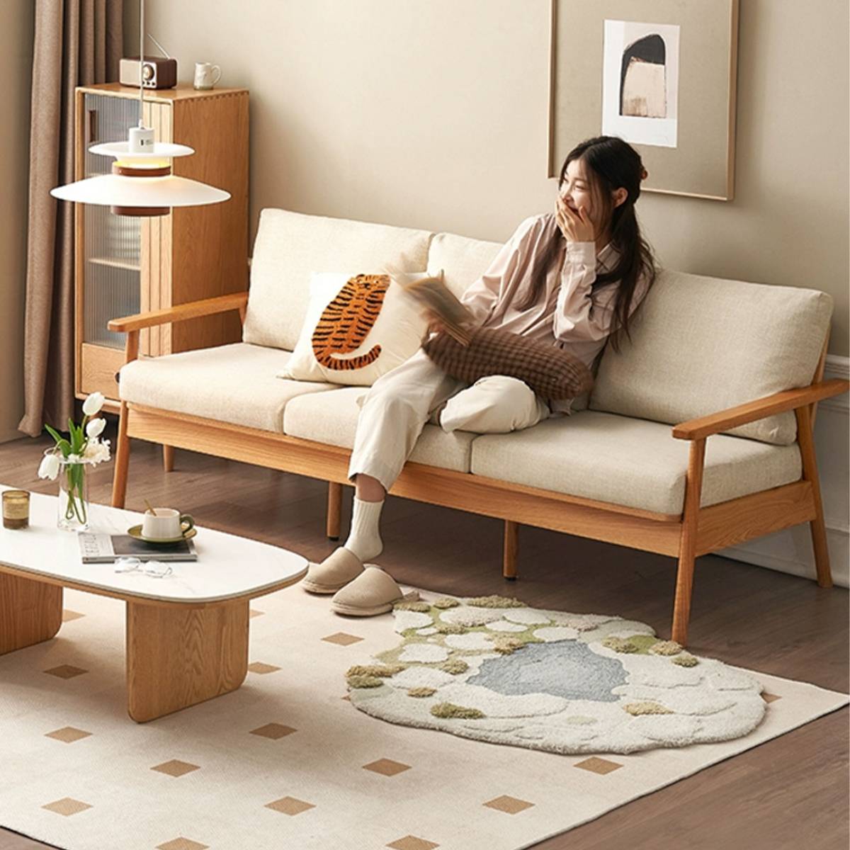 Woman reading on the sofa with beige cushions and a tiger pillow