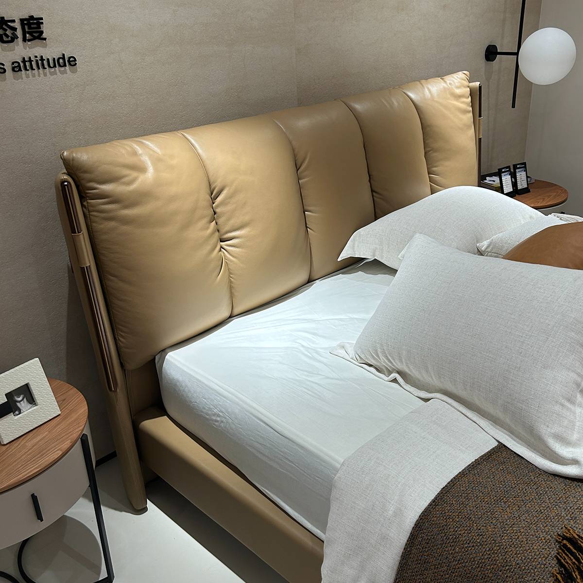 Full view of the beige leather bed with white bedding and side tables