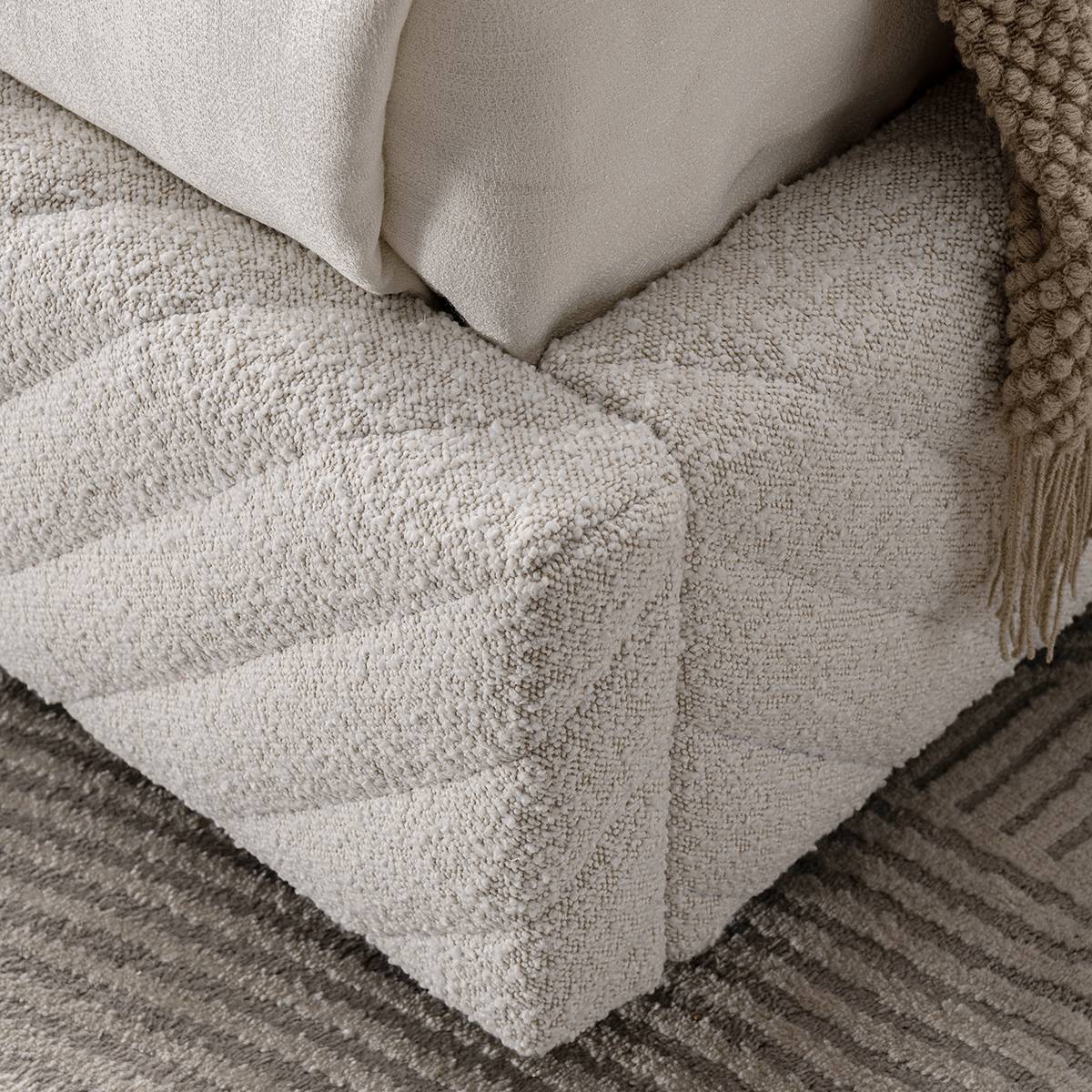 Close-up detail of the textured fabric and diamond tufting on the corner of the bed base.