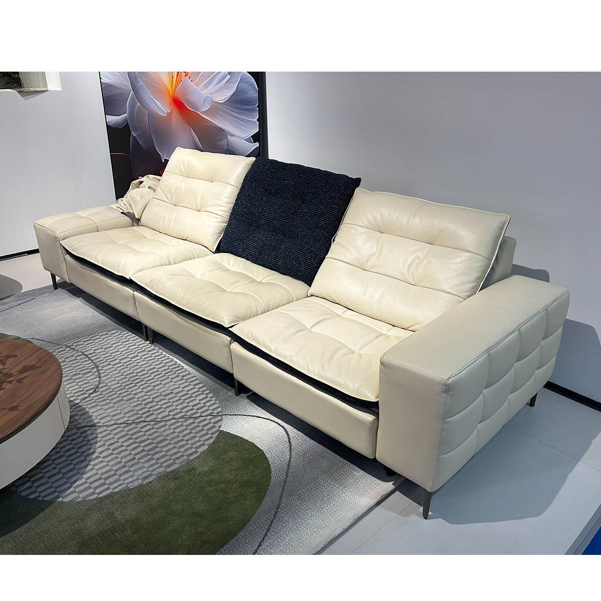 Full view of the cream-colored leather sofa with a black throw pillow