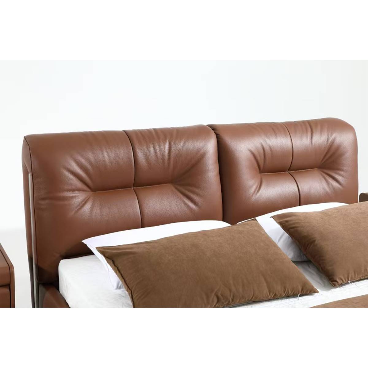 Full view of the brown leather bed with tufted headboard and pillows