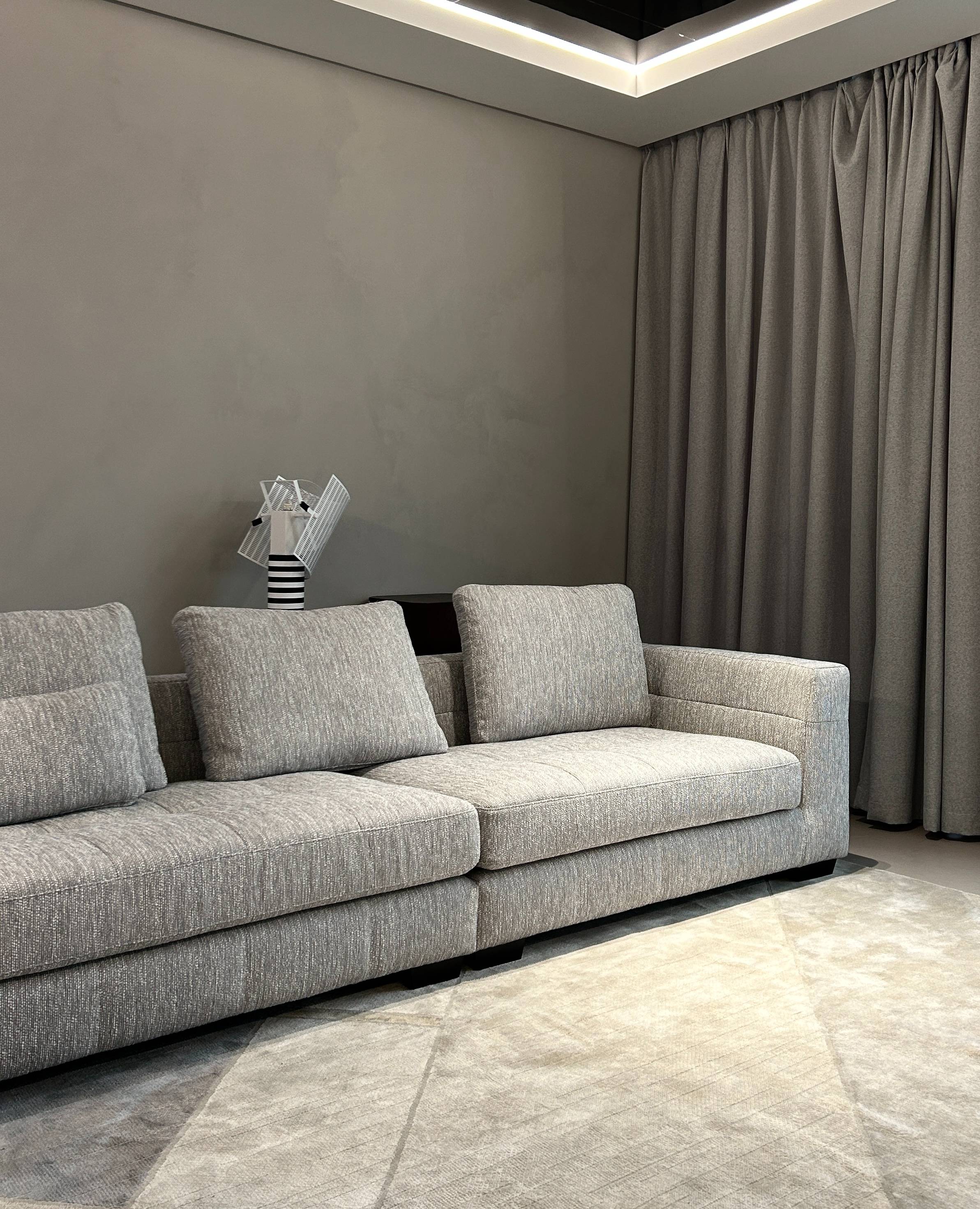 Grey fabric modular sofa in a living room setting with grey curtains