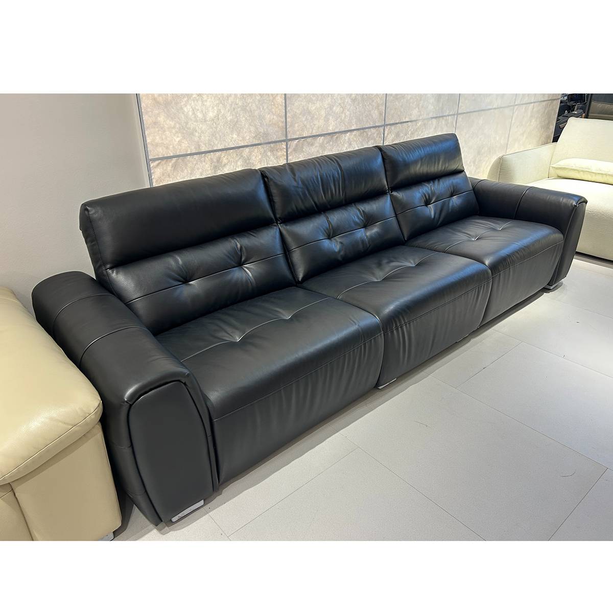 Full view of the black leather functional sofa in a showroom setting