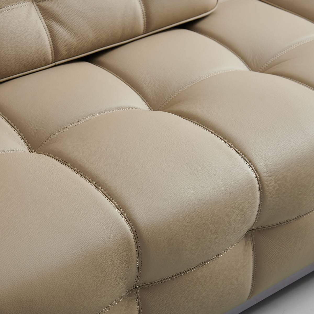 Close-up of beige tufted leather sofa seat cushions