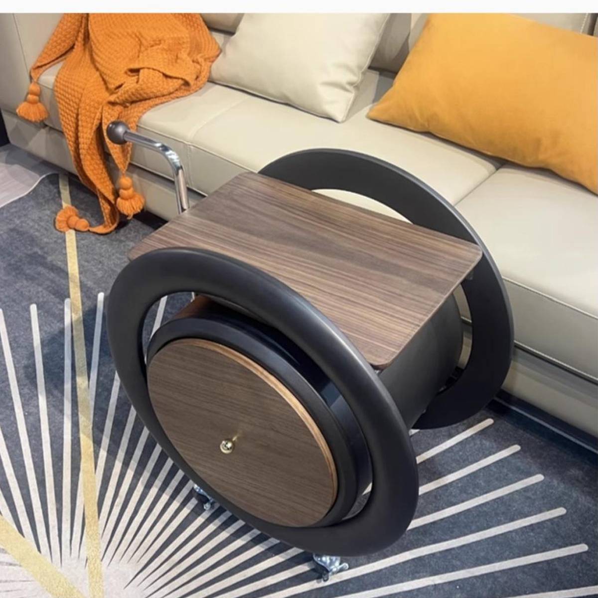 Top-down view of the rolling side table showing the wood veneer tabletop and circular frame design on a patterned rug.