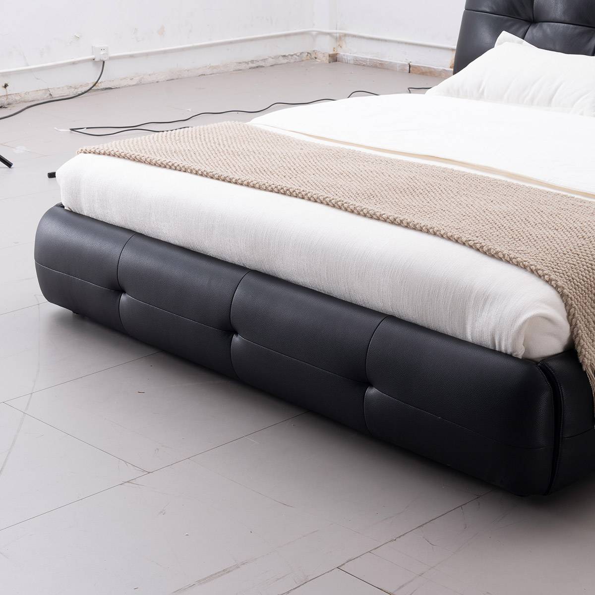 Close-up detail of the black leather upholstered bed base and white mattress