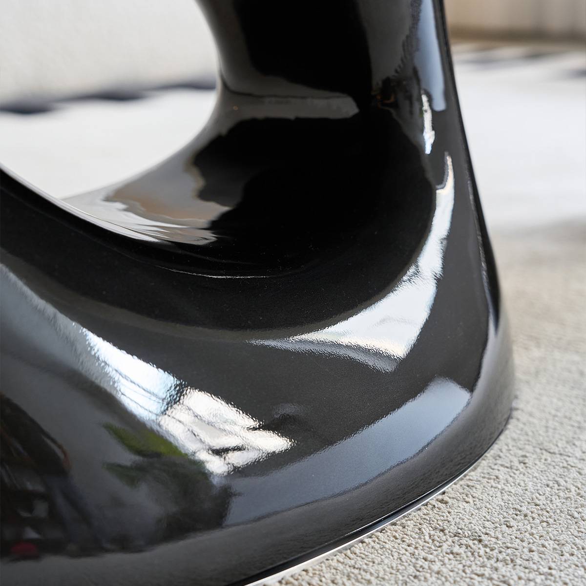 Close-up of the glossy black curved base of the coffee table