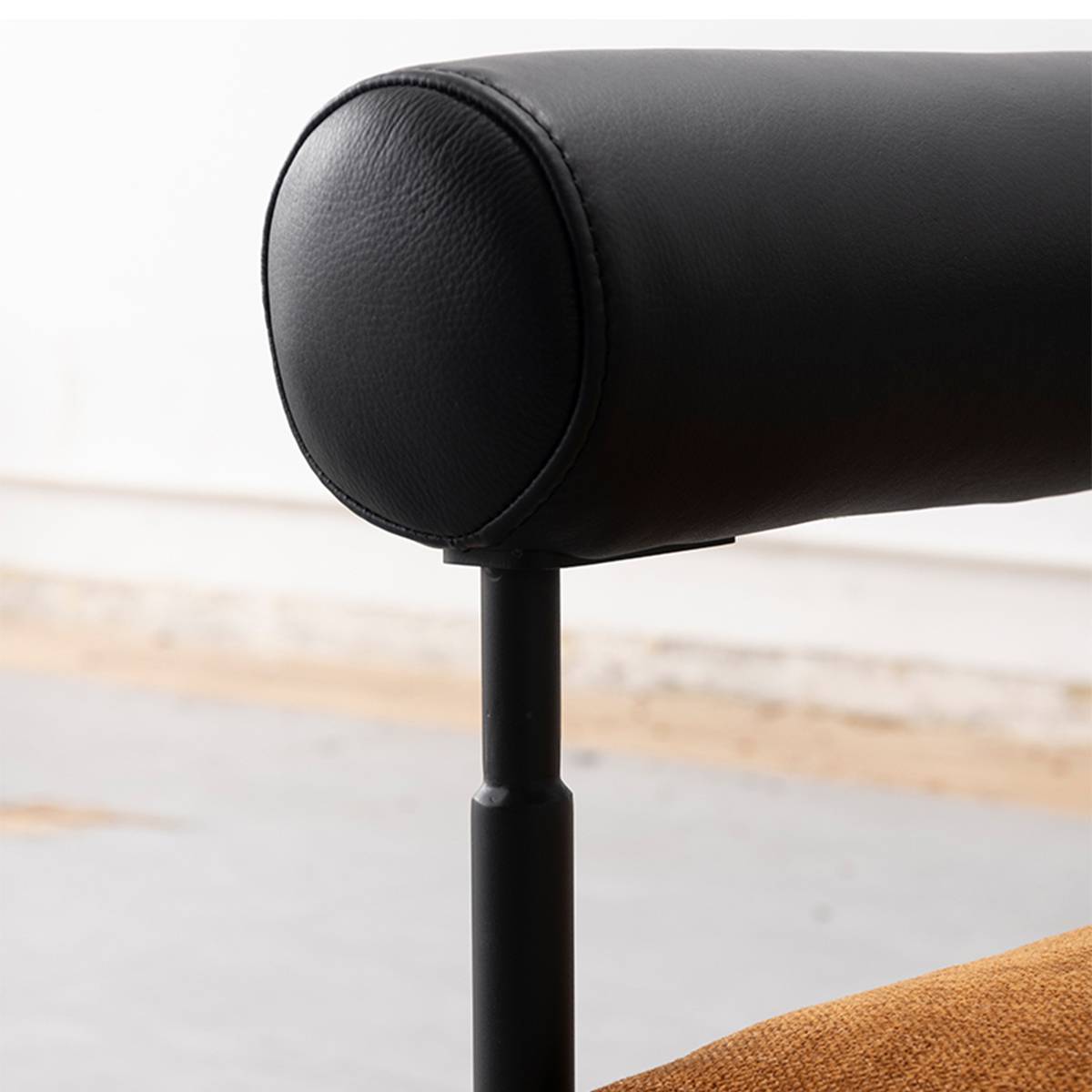 Full view of the modern lounge chair with curved black leather armrests and brown seat