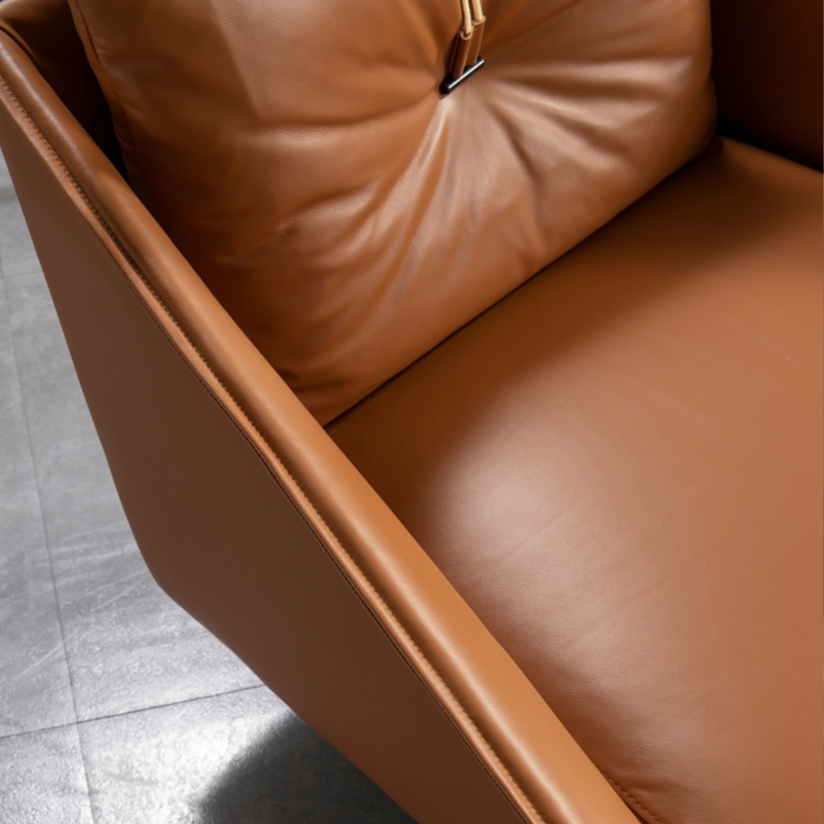 Close-up view of the brown leather armrest and seat cushion showing stitching details.