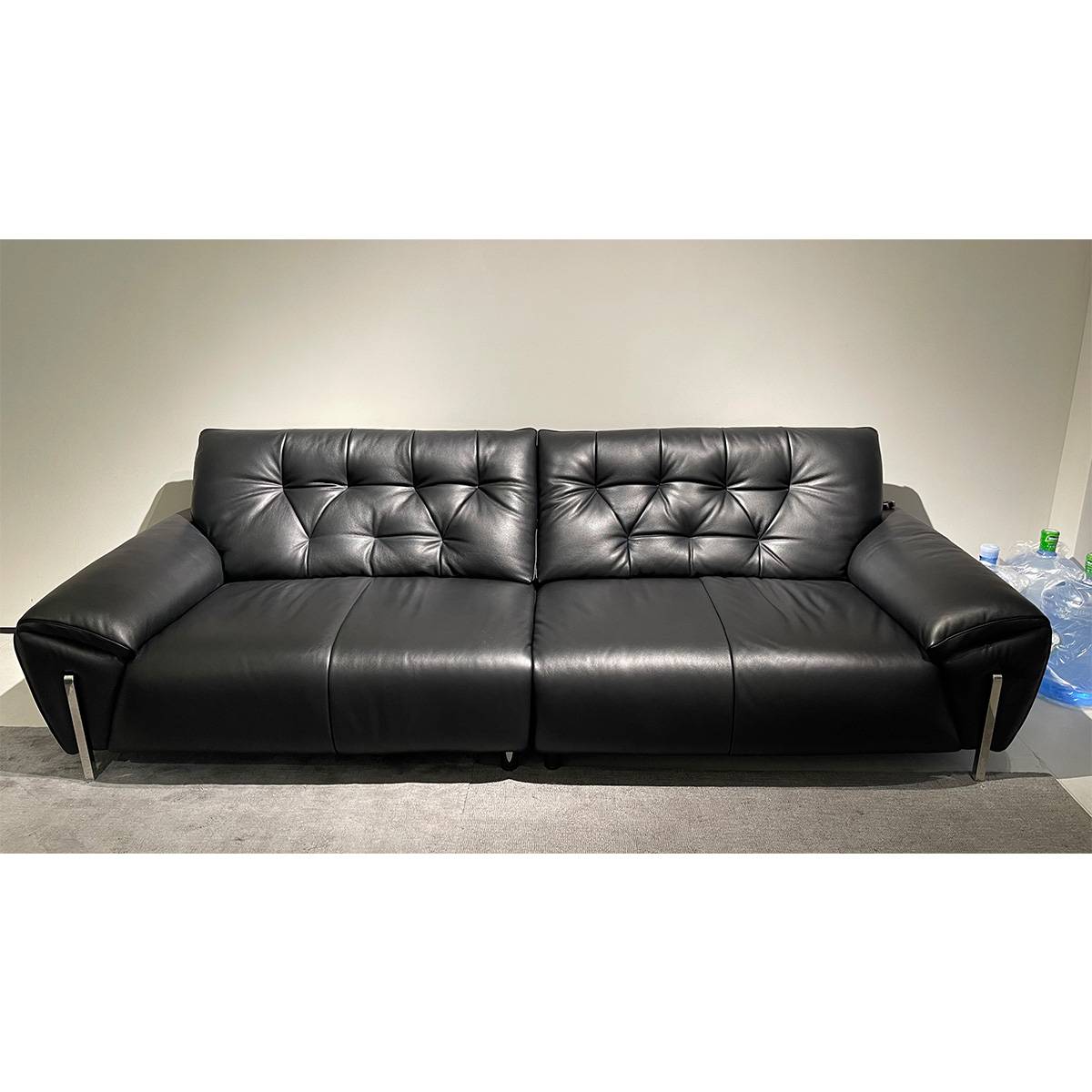 Front view of black leather sofa showing tufted details