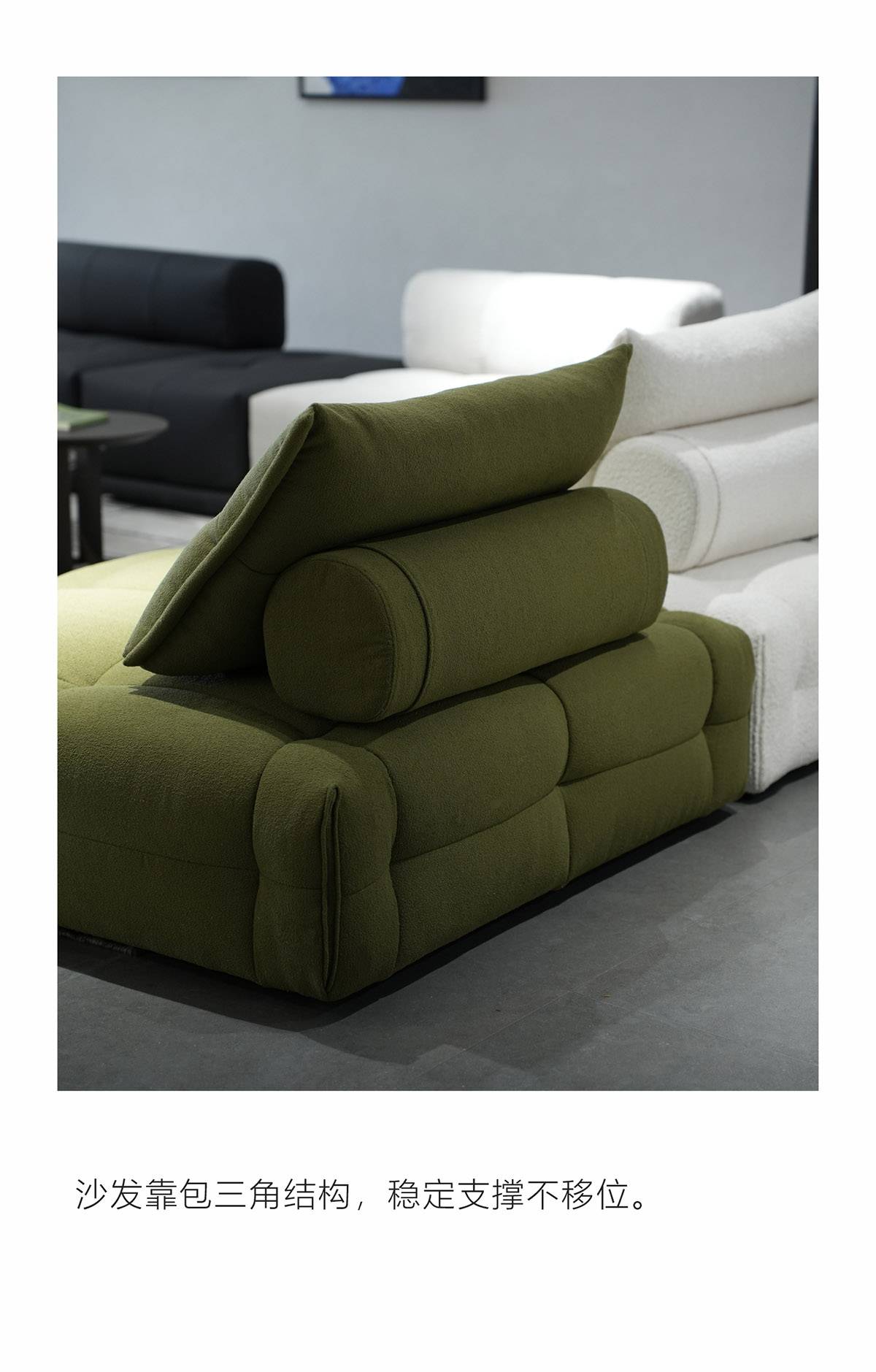 Close-up of the green fabric sofa showing the triangular back cushion structure and cylindrical bolster pillow.