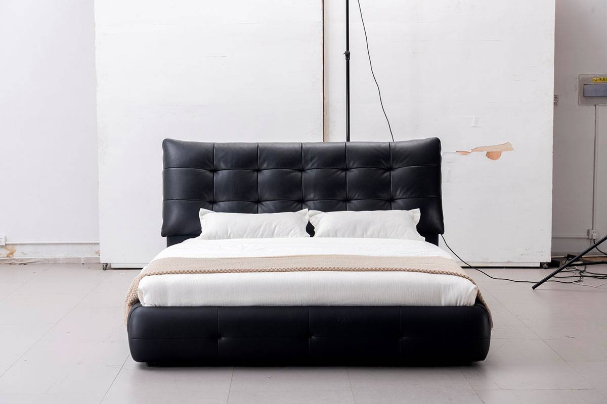 Front view of the black leather tufted bed with white bedding.