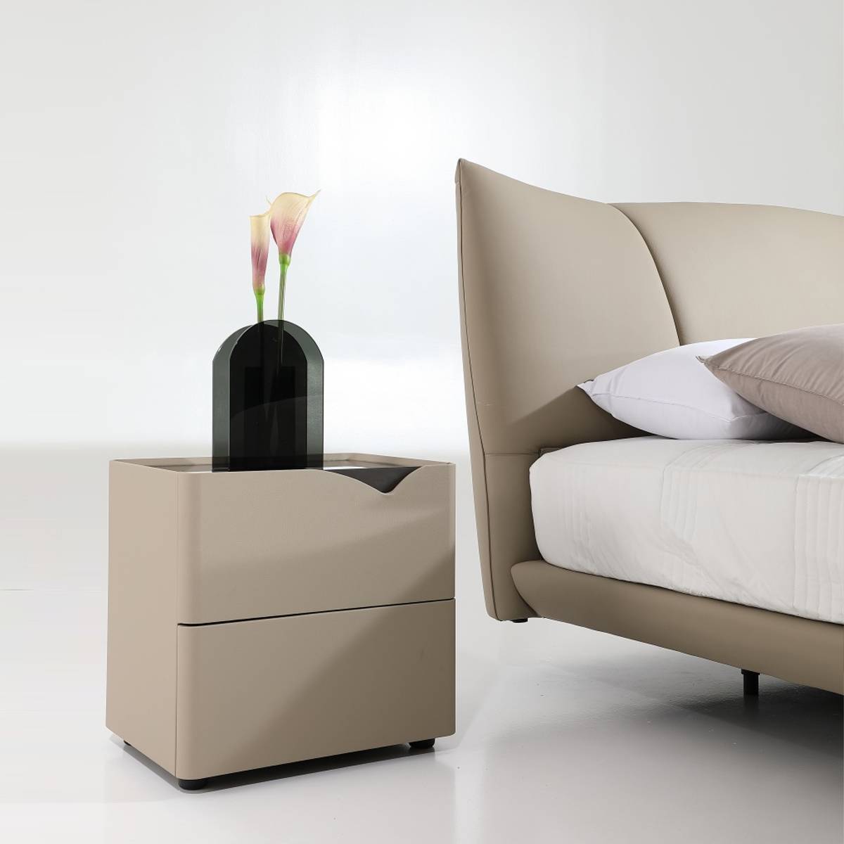 Side view of the beige leather bed with a matching bedside table and vase