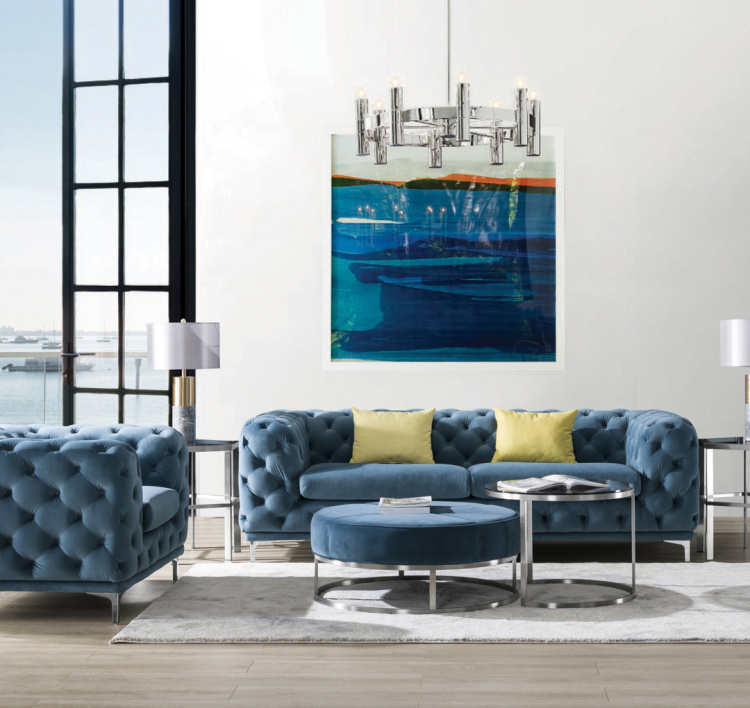 Living room setup featuring a blue tufted sofa with yellow cushions and silver accents