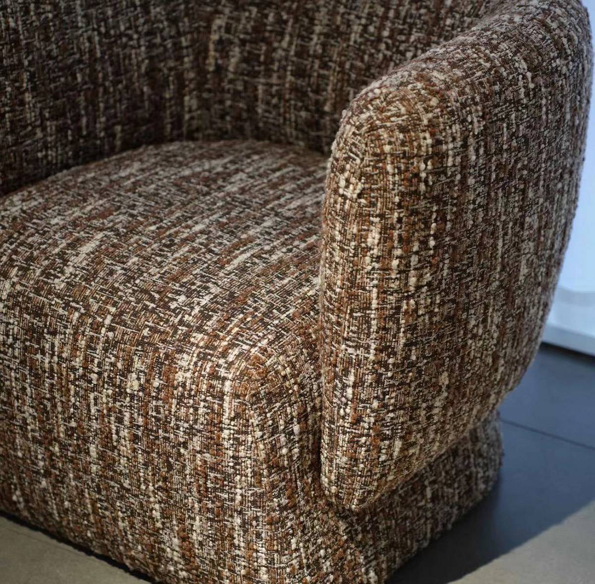 Close-up detail of the chair seat and armrest showing the brown woven fabric texture.