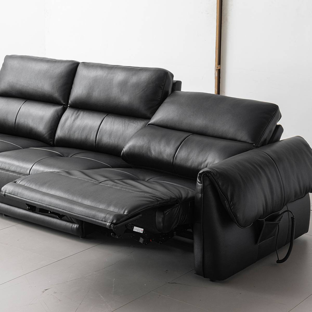 Black leather sofa with one seat reclined showing the mechanism