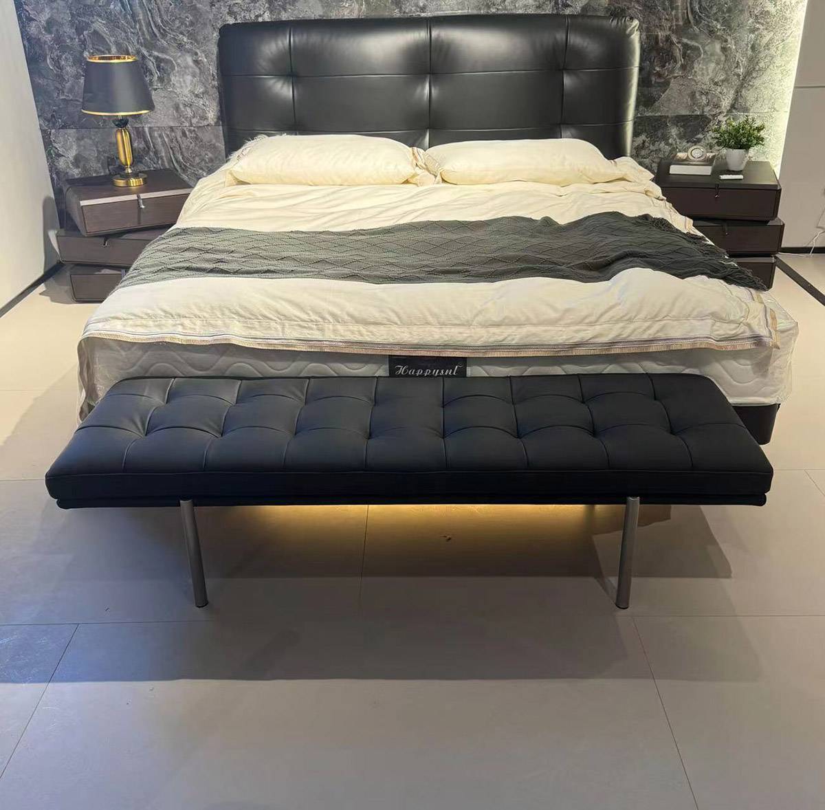 Front view of the bed bench positioned at the foot of a bed with a black headboard.